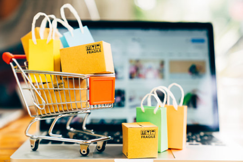 A trolley with shopping bags within it sat on top of a laptop